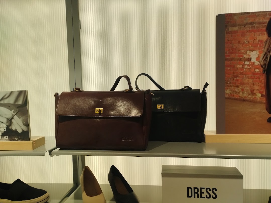 Two stylish leather briefcases, one brown and one black, displayed on a shelf with shoes below.