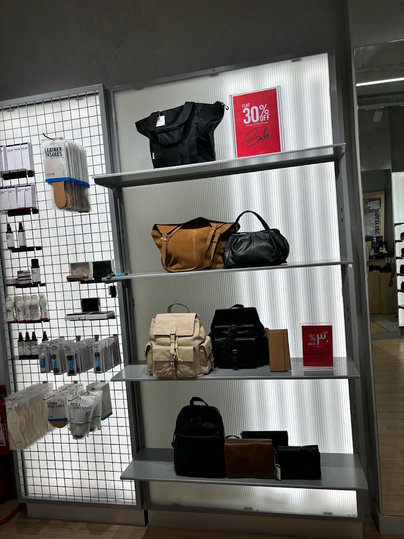 Clarks shop interior displaying bags, backpacks, and shoe care products with a sale sign.
