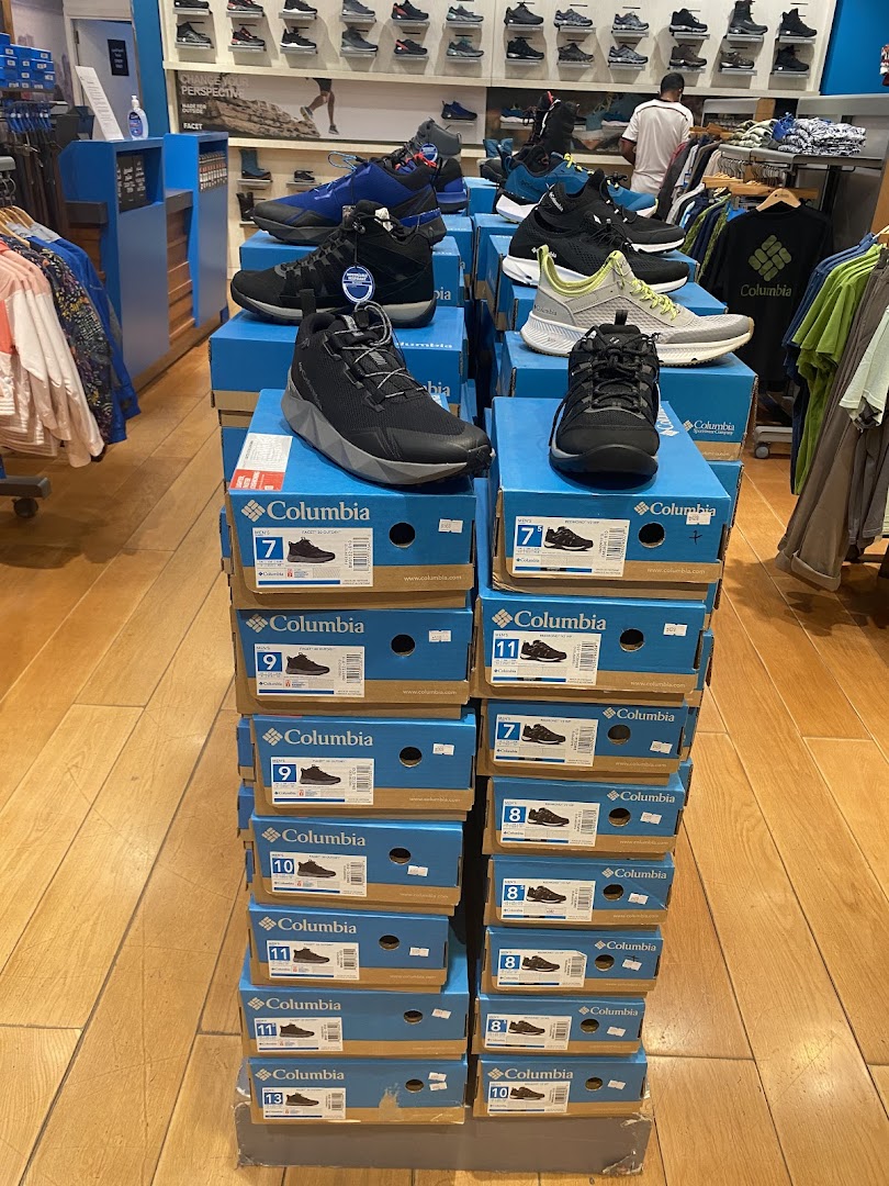 A display of Columbia brand shoes in various sizes stacked on blue boxes inside a store.