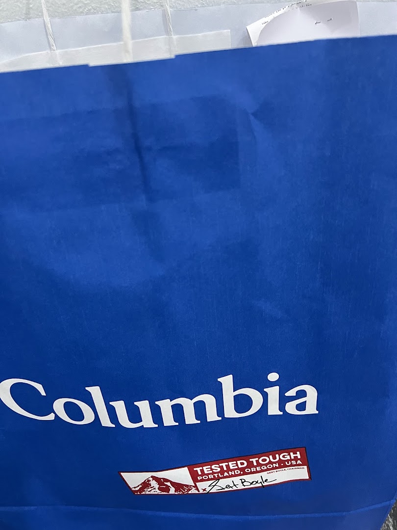 A blue shopping bag with the Columbia logo and a 'Tested Tough' label.