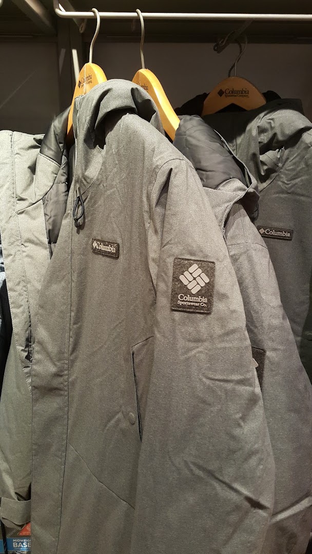 Close-up of Columbia brand jackets hanging on wooden hangers.