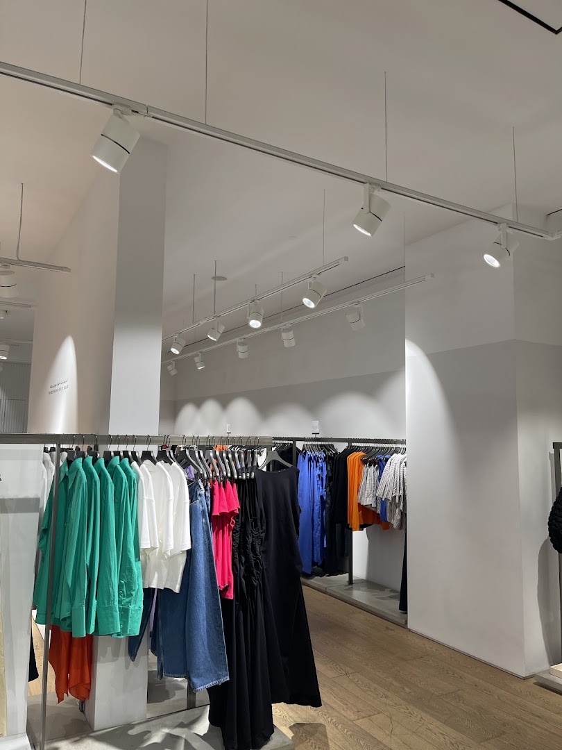 Interior view of a COS store showcasing a variety of colorful clothing on racks.