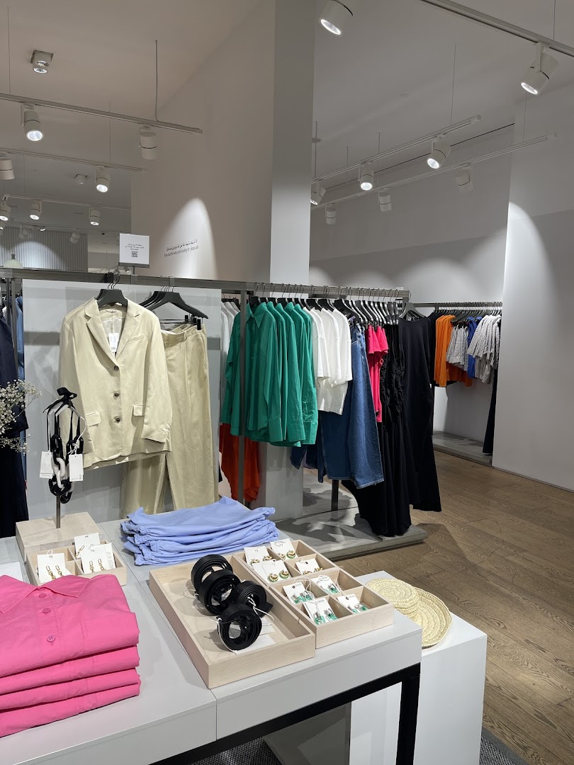 Interior view of a COS clothing store showcasing a variety of apparel and accessories.