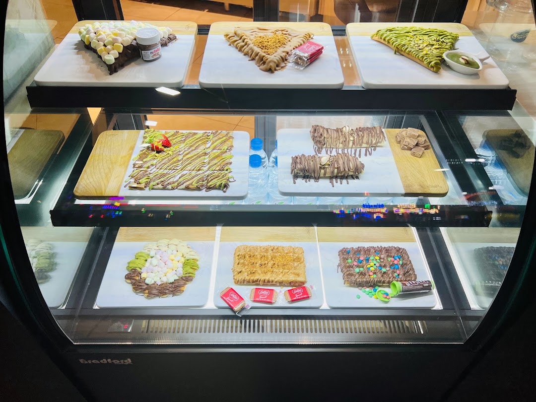 A display case filled with various sweet crepes and desserts, showcasing different toppings and fillings.