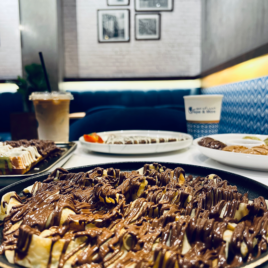 A close-up of delicious crepes and waffles generously drizzled with chocolate sauce.