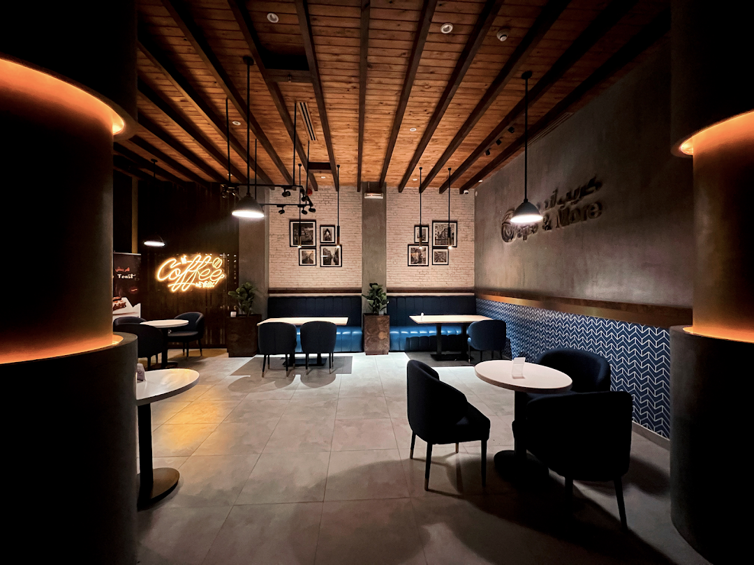 Interior view of a modern cafe with wooden ceilings, comfortable seating, and neon signage.