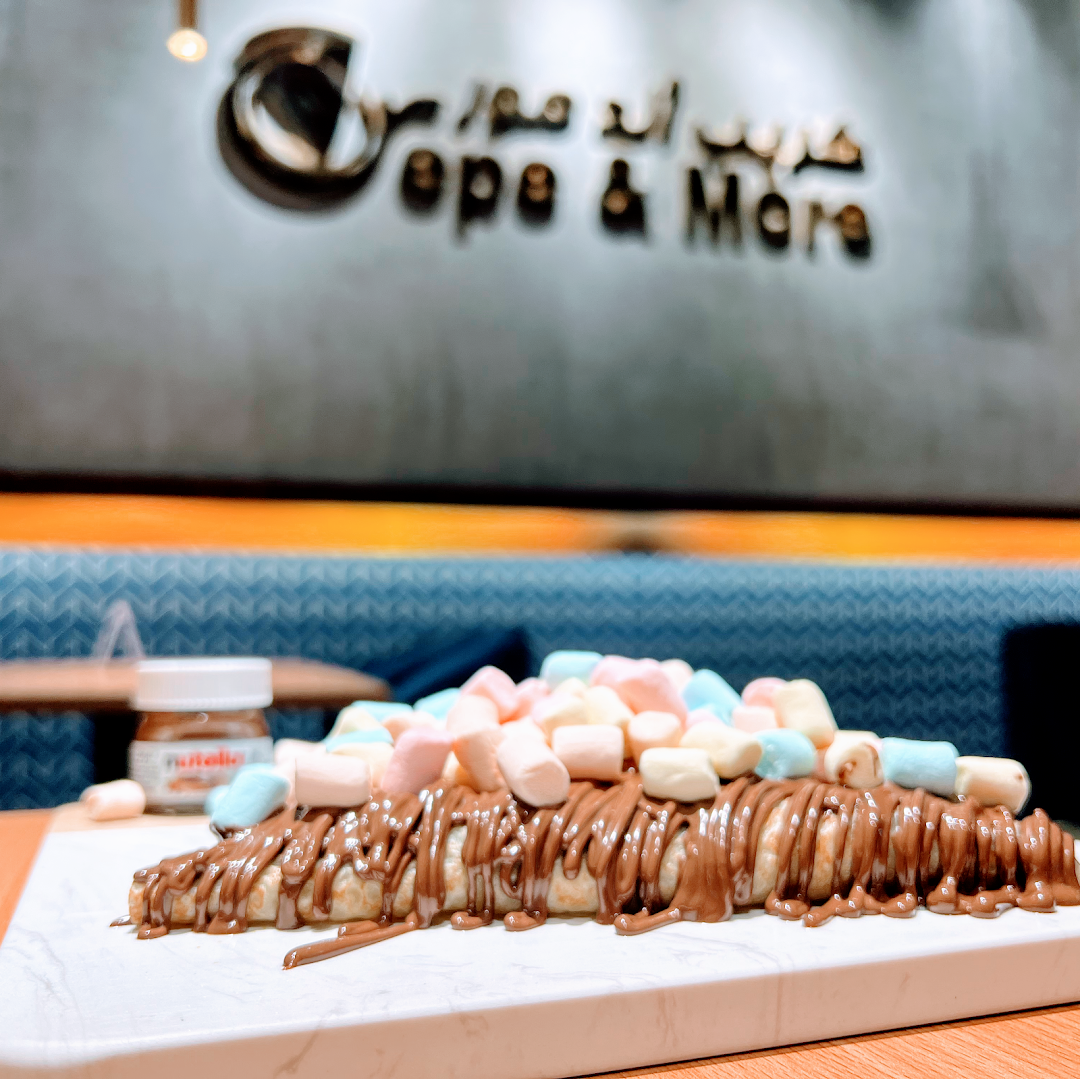 A delicious crepe topped with chocolate sauce and colorful marshmallows.