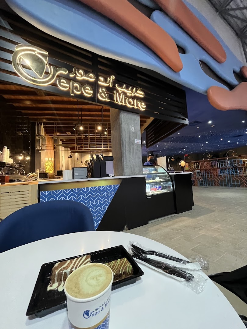 A table with crepes and a coffee cup in front of the Crepe & More shop.