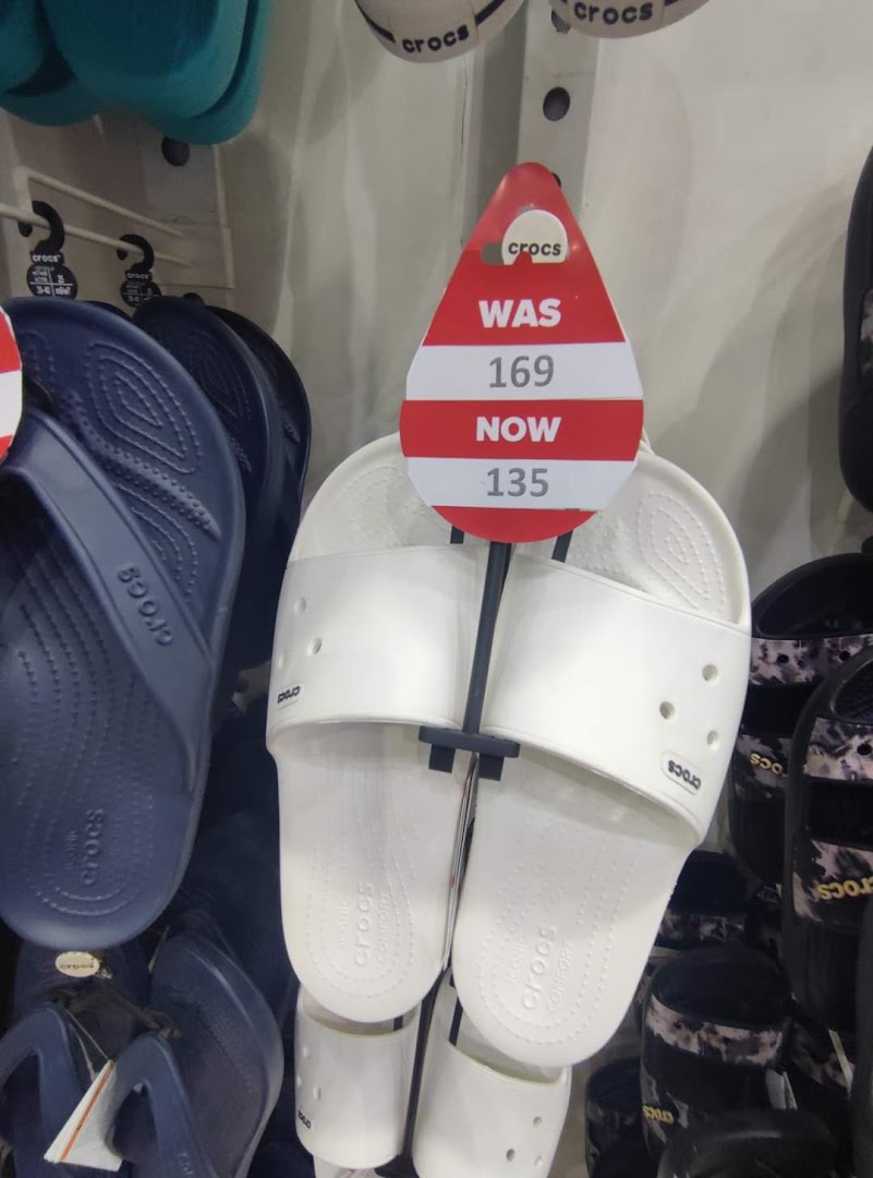 Crocs sandals on display with a sale tag showing a price reduction.
