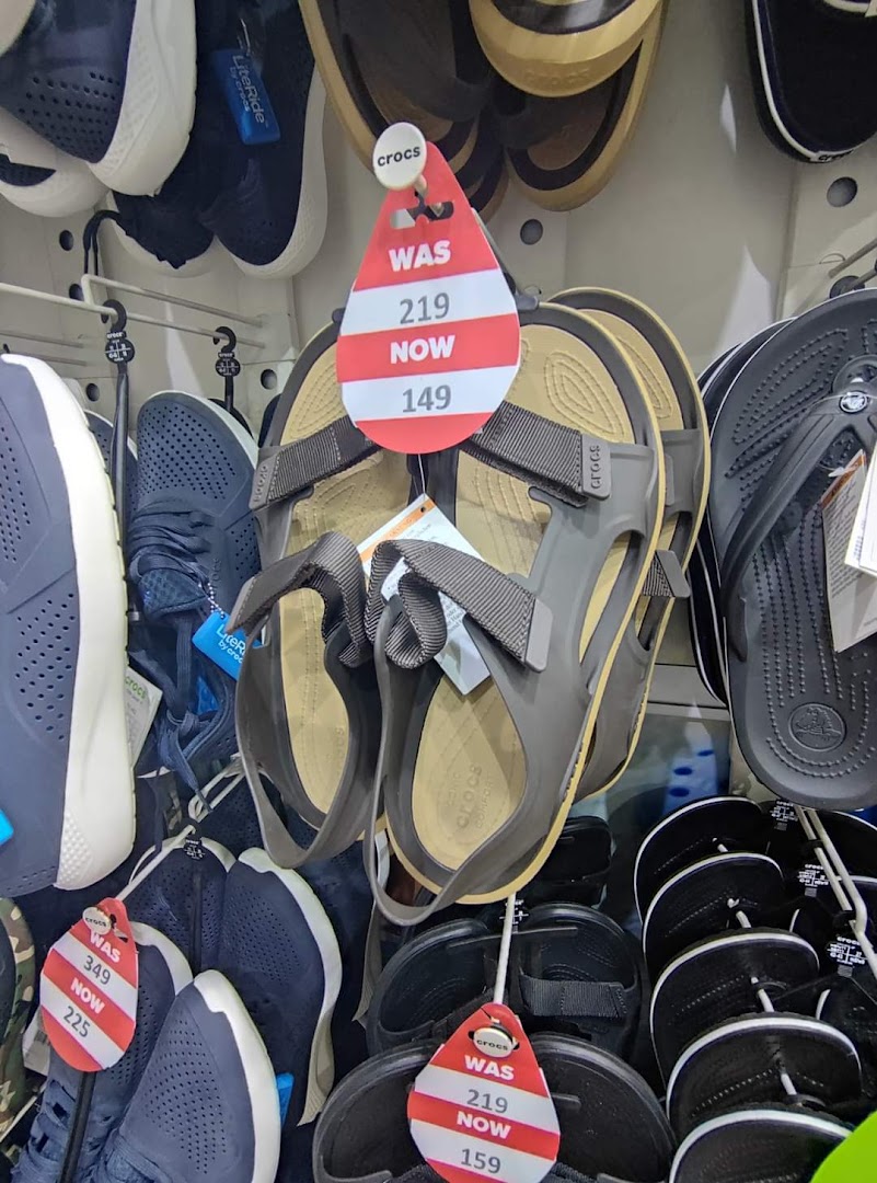 A display of Crocs sandals and flip-flops with sale price tags.