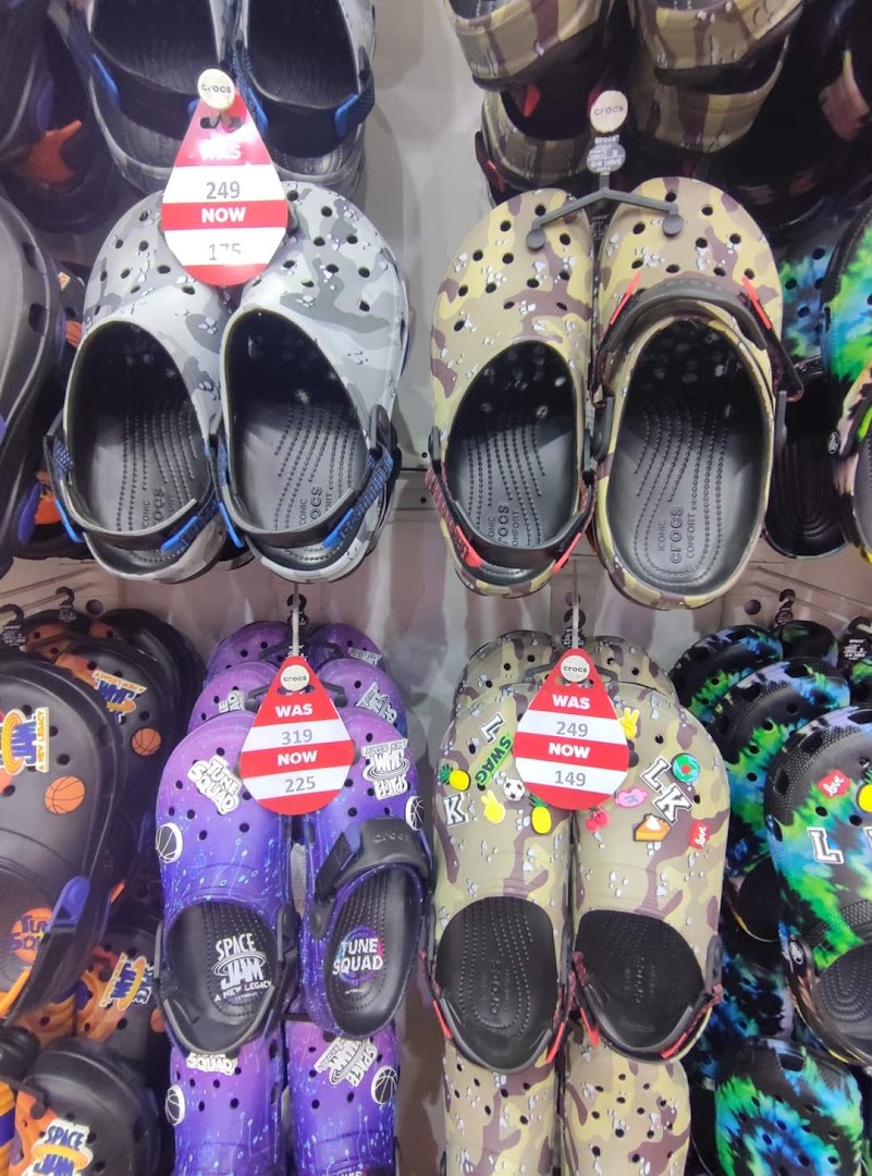 A display of various Crocs shoes with different patterns and sale tags.