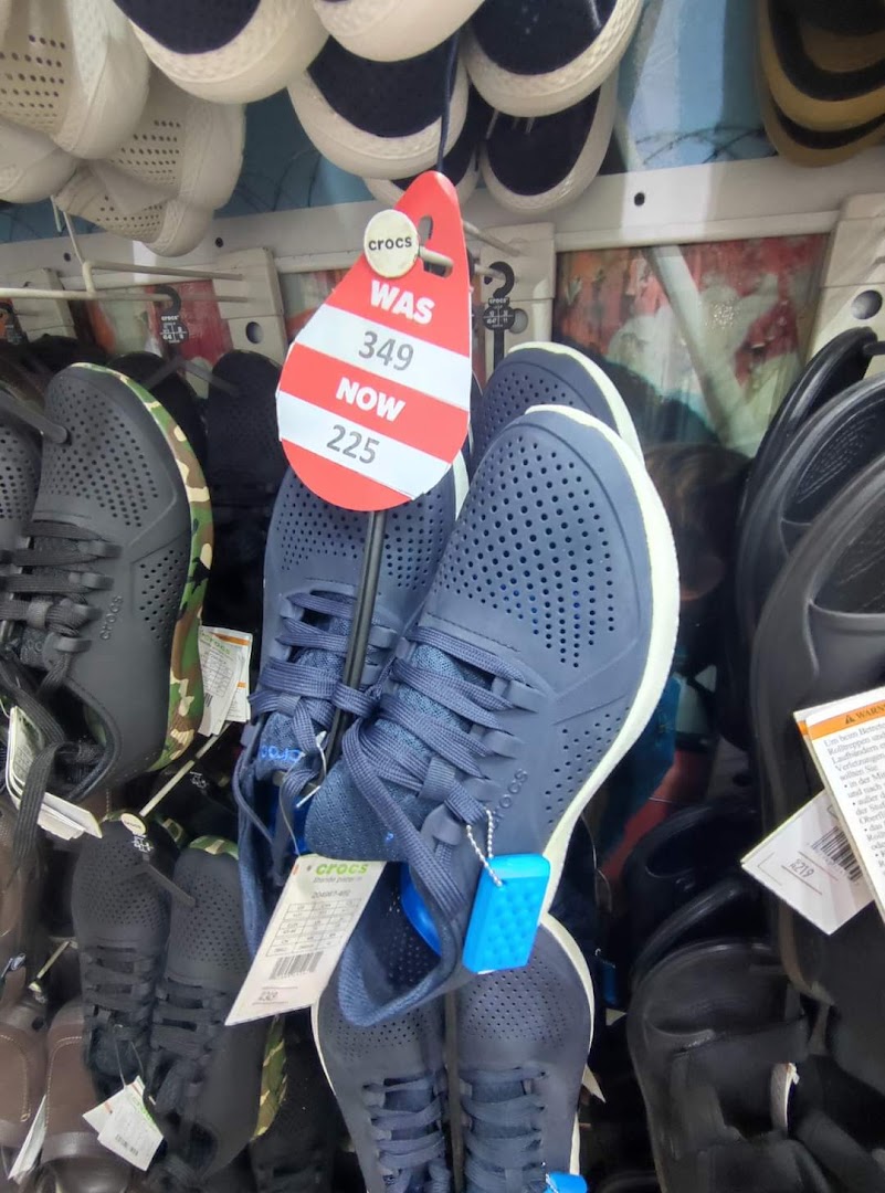 A display of Crocs shoes with a sale tag showing a price reduction.