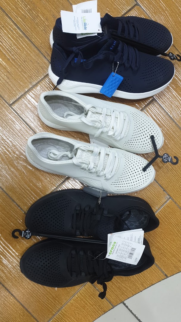 A display of three pairs of Crocs LiteRide sneakers in navy, white, and black.