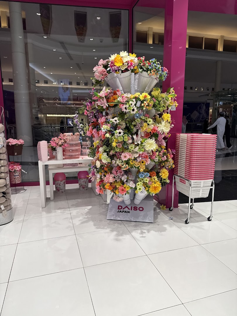 A vibrant display of artificial flowers outside a Daiso Japan store.