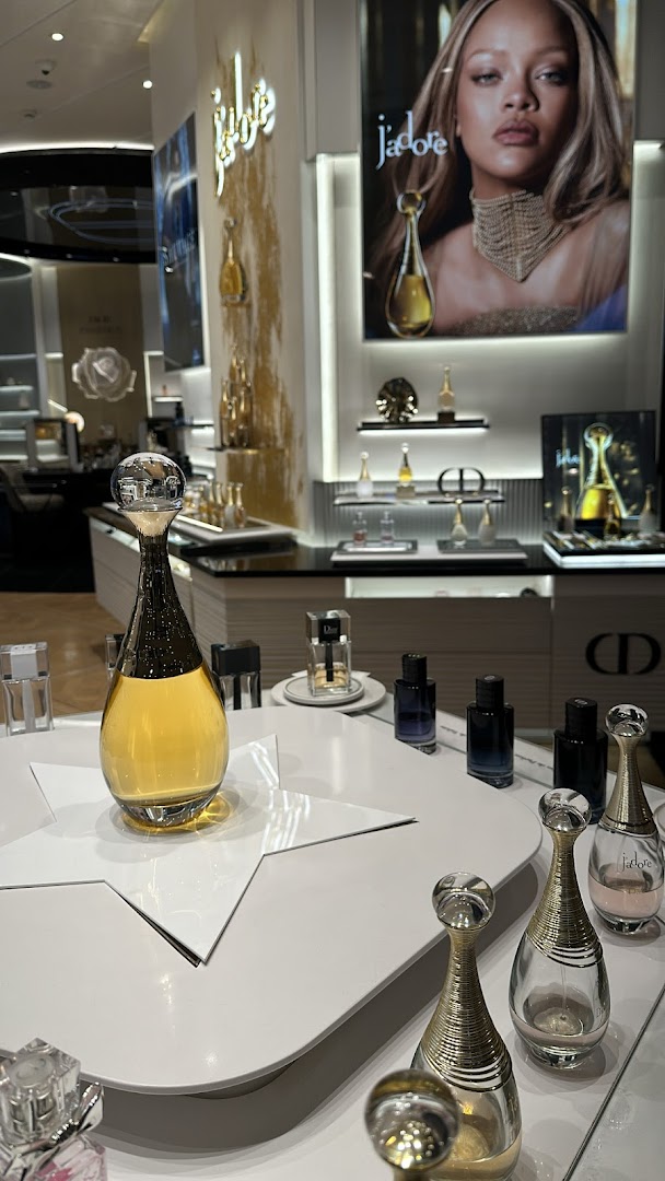 Dior J'adore perfume display featuring iconic bottles and a campaign image.