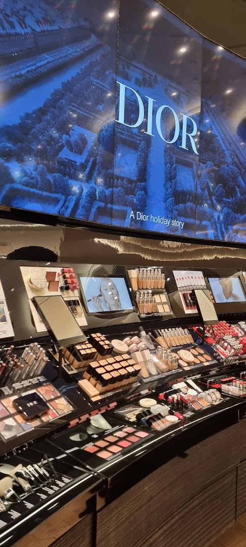 Dior makeup display featuring various foundations, lipsticks, and eyeshadow palettes.