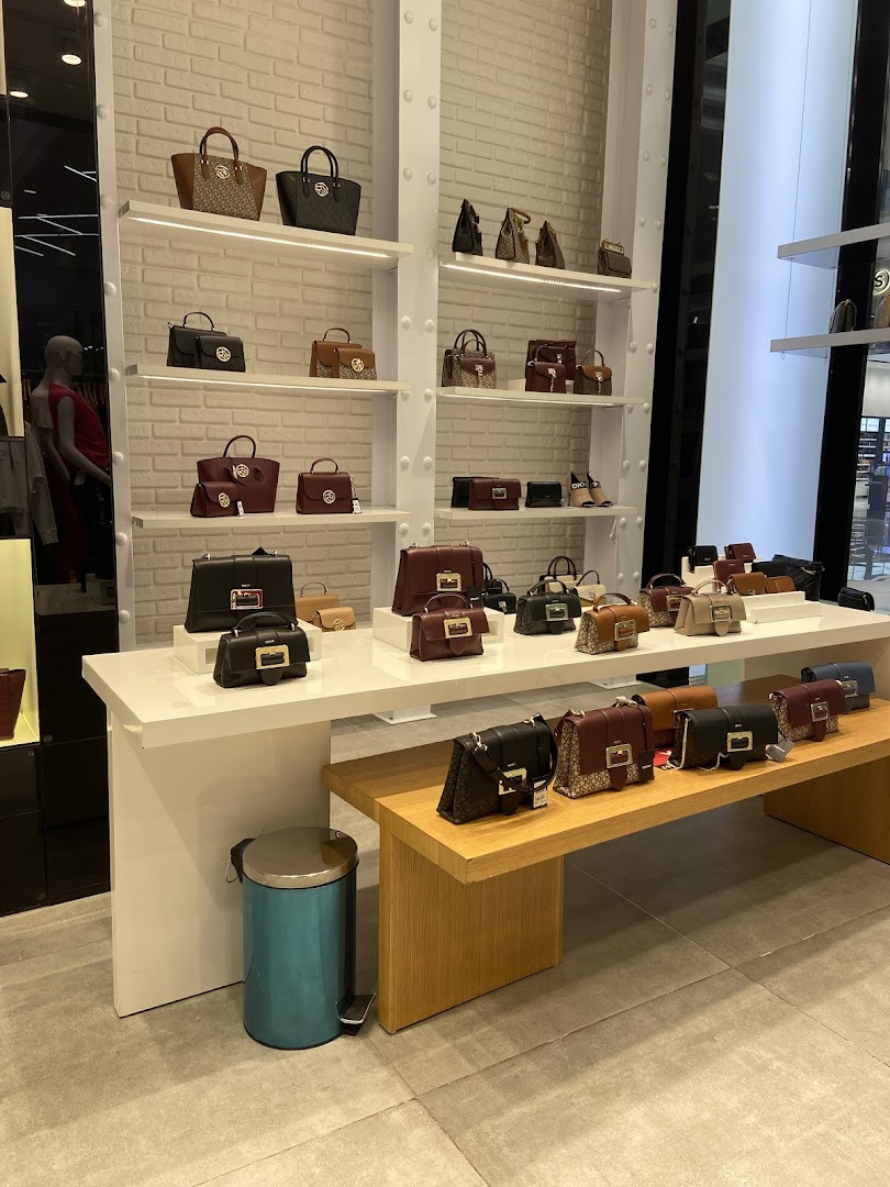 A display of various DKNY handbags on shelves and a wooden bench.