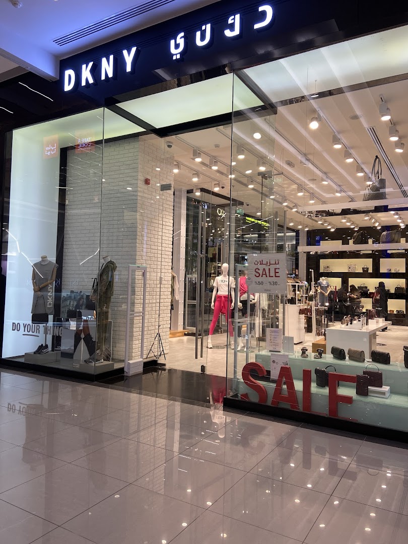 The exterior of a DKNY store with mannequins and a large 'SALE' sign.