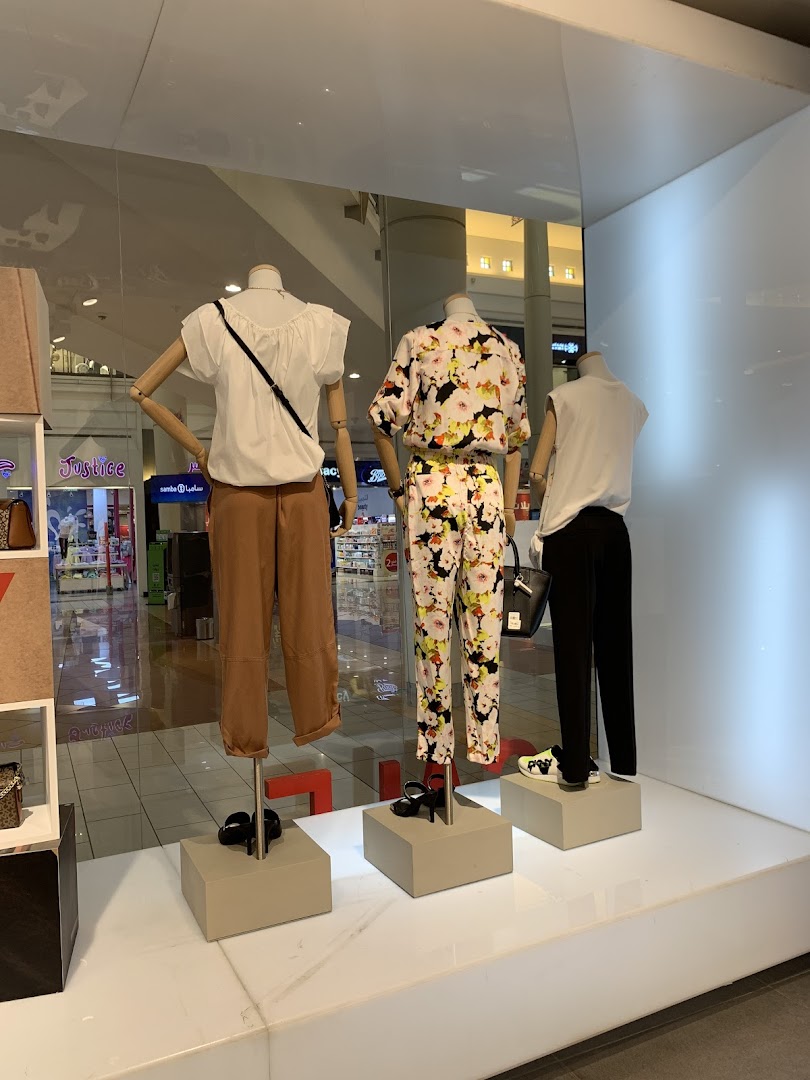 Mannequins display stylish outfits in a shop window, showcasing fashion.