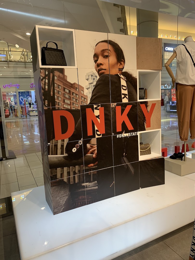 DKNY store display featuring a model, handbags, and the brand logo.