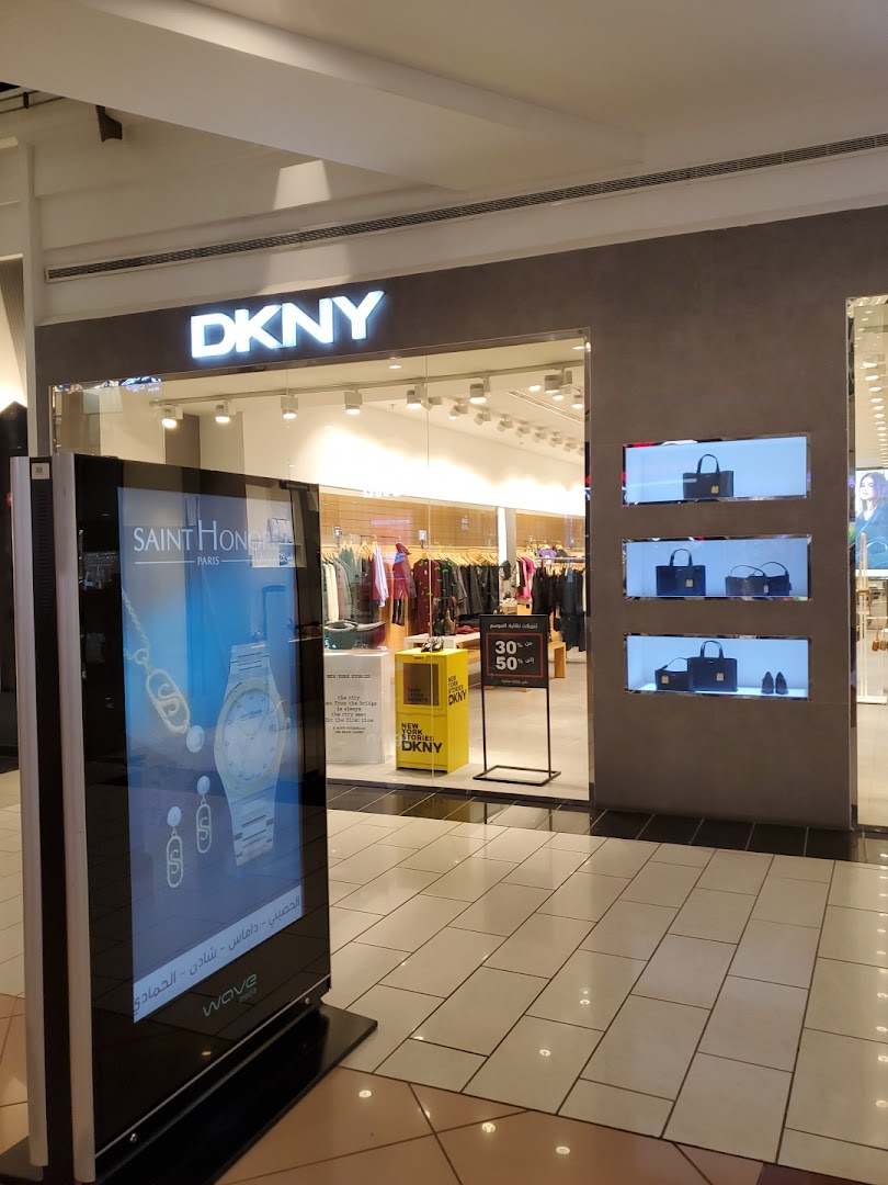 The DKNY store entrance with merchandise displayed inside and a digital advertisement outside.