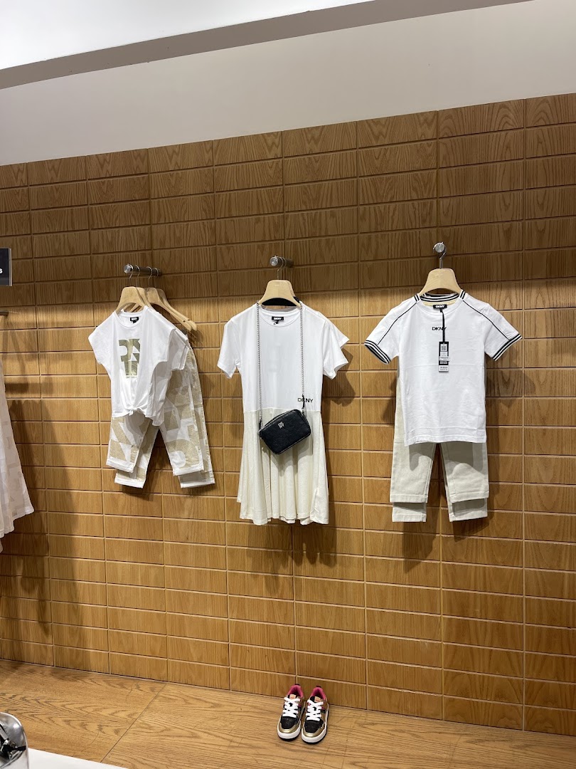 DKNY store display featuring children's clothing, a handbag, and sneakers.