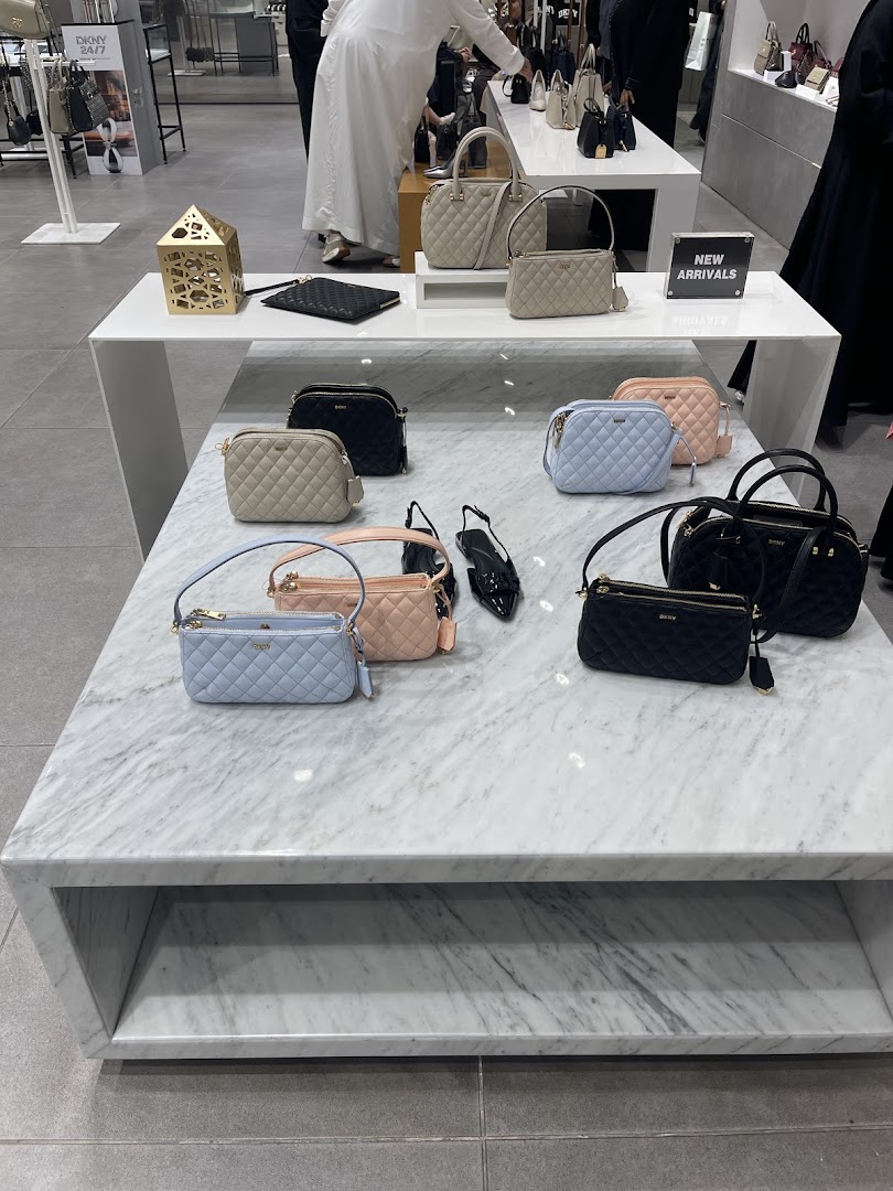 DKNY shop interior displaying quilted handbags in various colors on display tables.