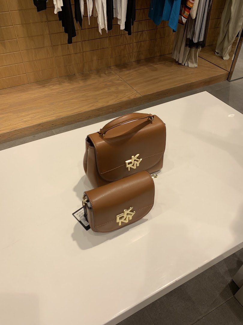 Two brown DKNY handbags with gold logos displayed on a white surface.