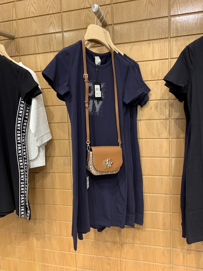 DKNY store interior with navy dresses and a small crossbody bag.