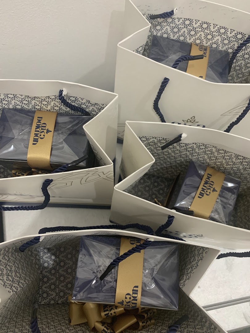 Several white shopping bags with blue rope handles, each containing a gift-wrapped item.