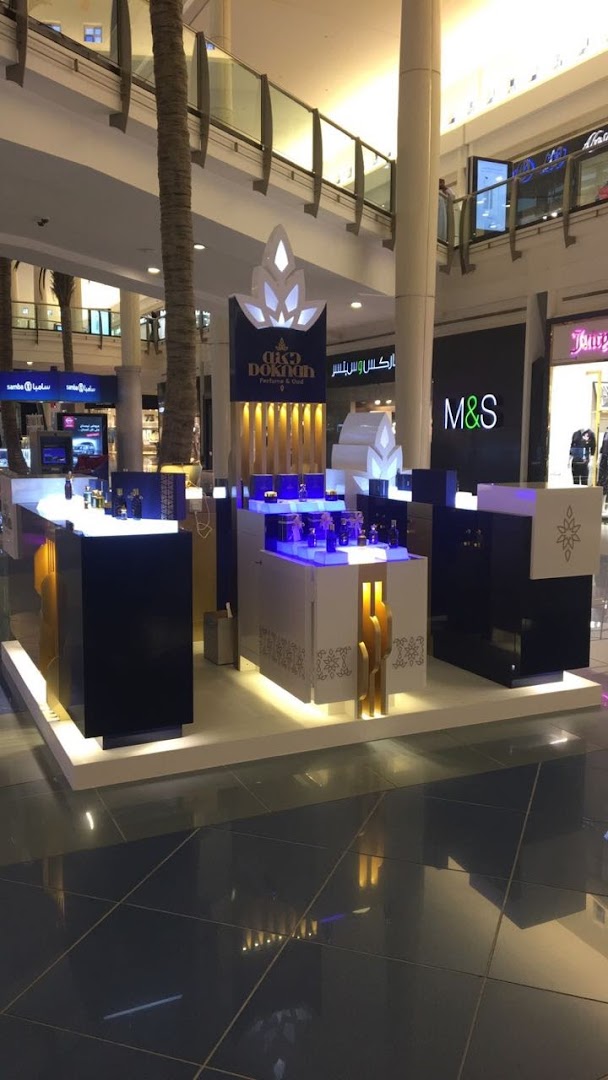 A modern retail kiosk displaying perfumes and oud products in a shopping mall.