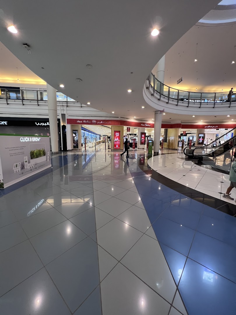 A wide shot of a modern shopping mall interior with shops and escalators visible.