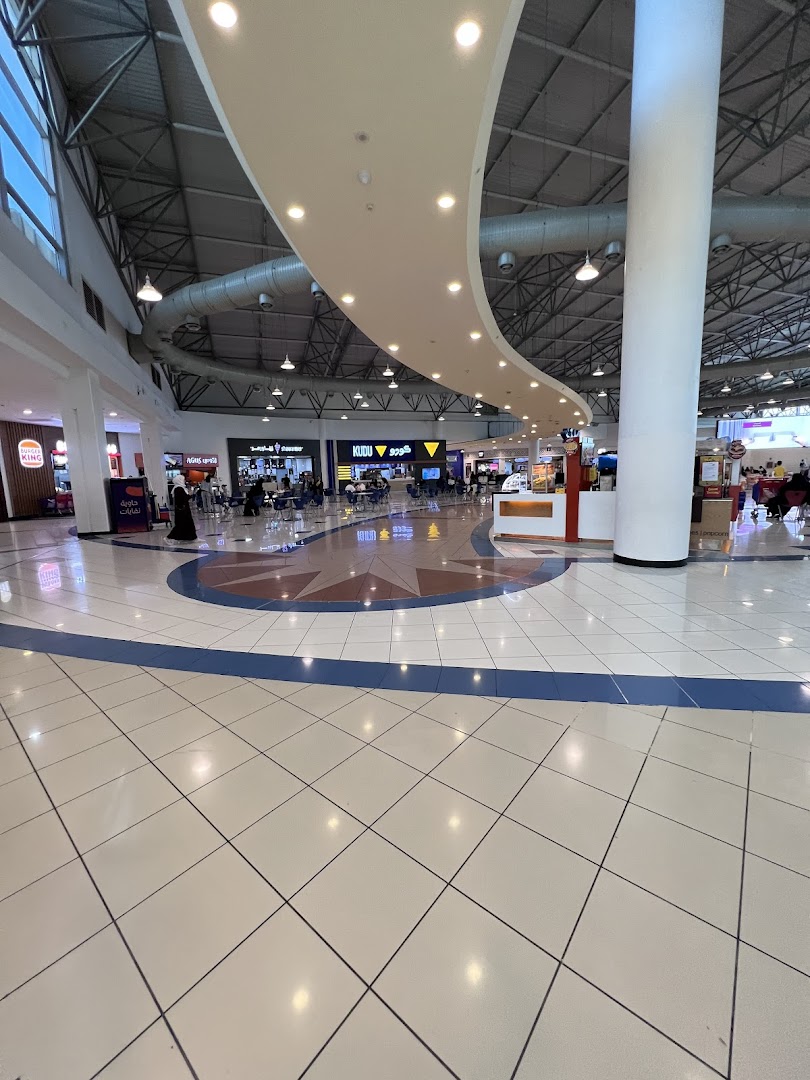 A wide view of a modern shopping mall interior with various shops and seating areas.