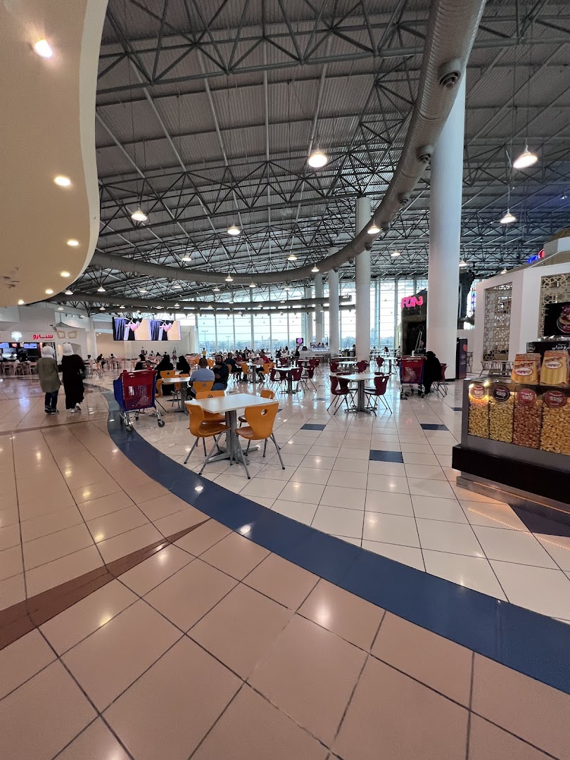 A wide shot of a busy food court with tables, chairs, and people dining.