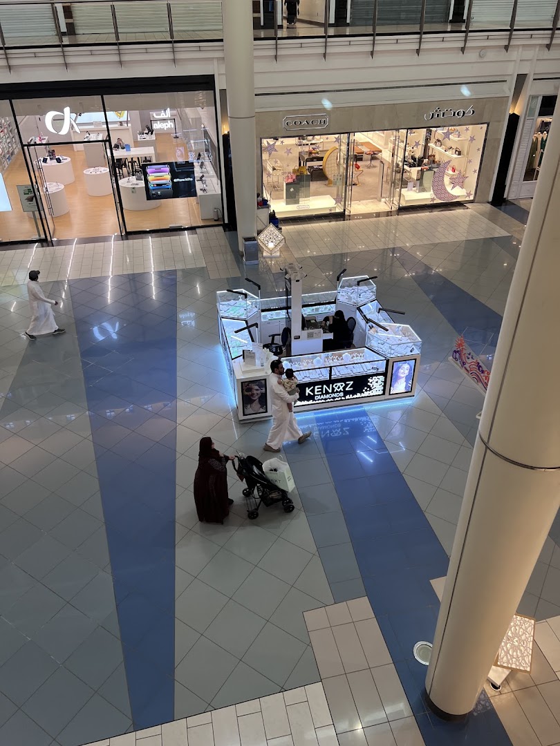 A view from above of a shopping mall interior with several shops and a kiosk.