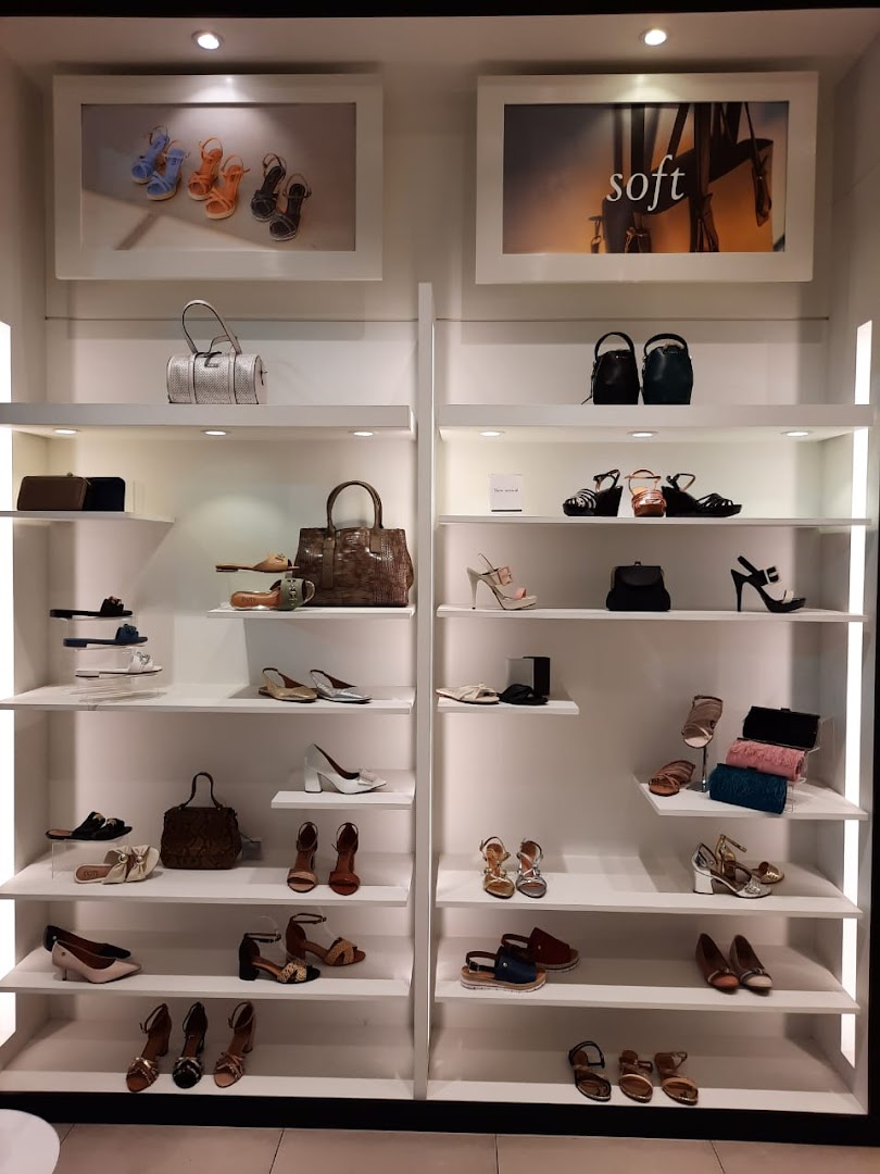 A well-lit display of women's shoes and handbags on white shelves.