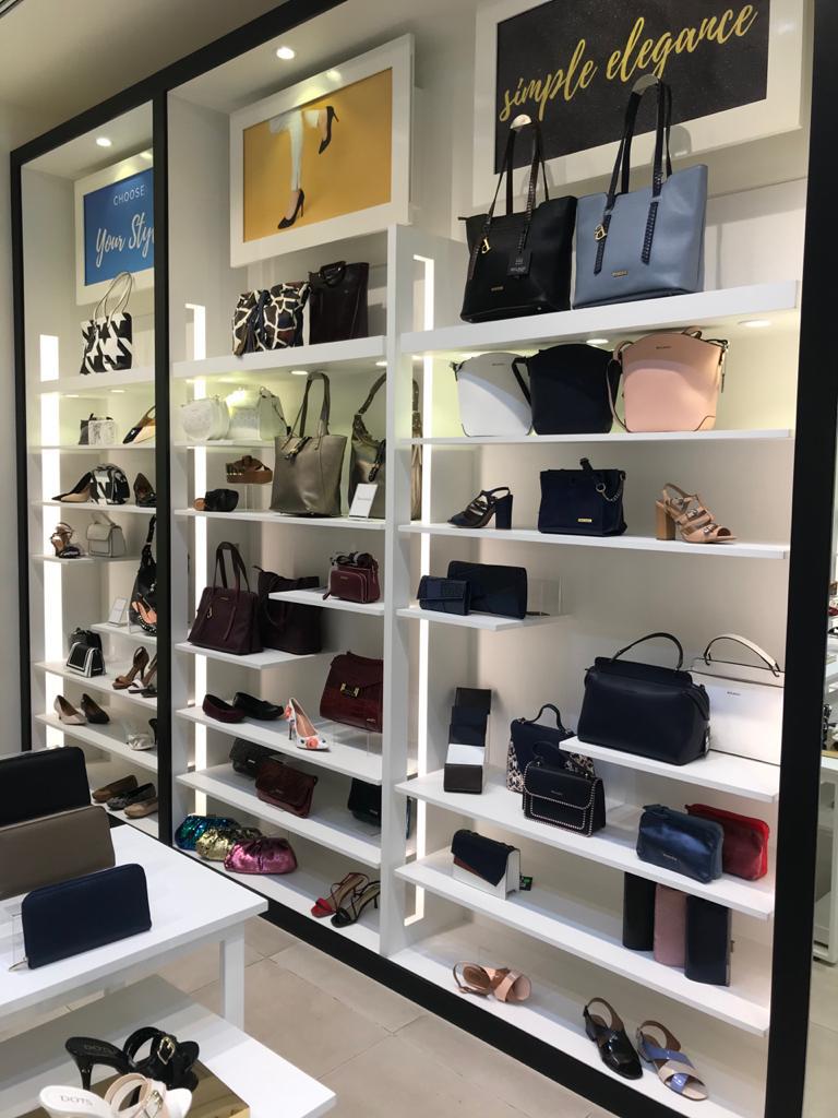 A well-lit retail display showcasing a variety of handbags and shoes on shelves.