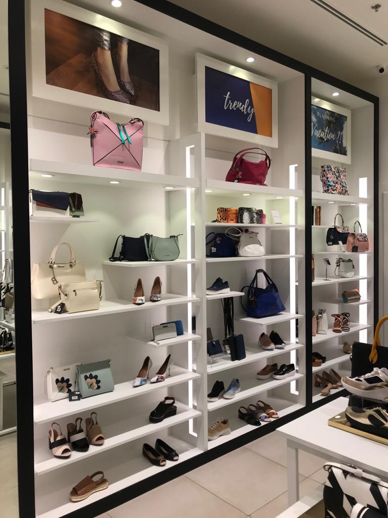 A well-lit retail display showcasing a variety of handbags and shoes on shelves.