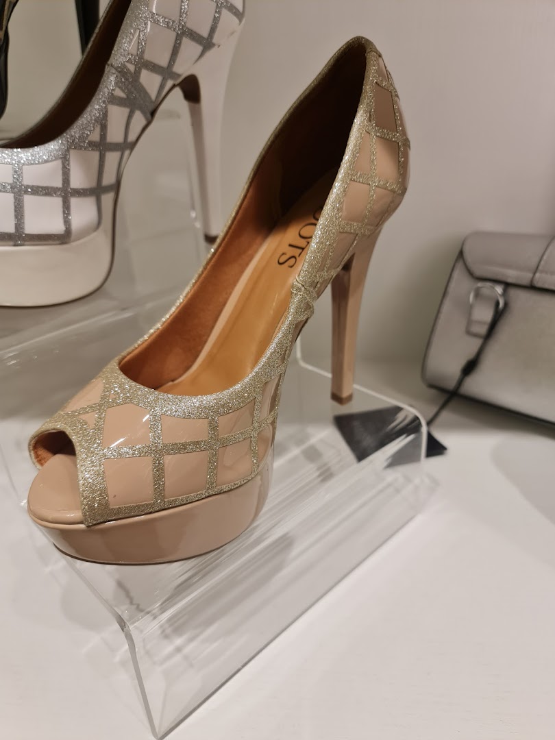 A close-up of a beige peep-toe high heel shoe with glitter detailing and a platform sole.