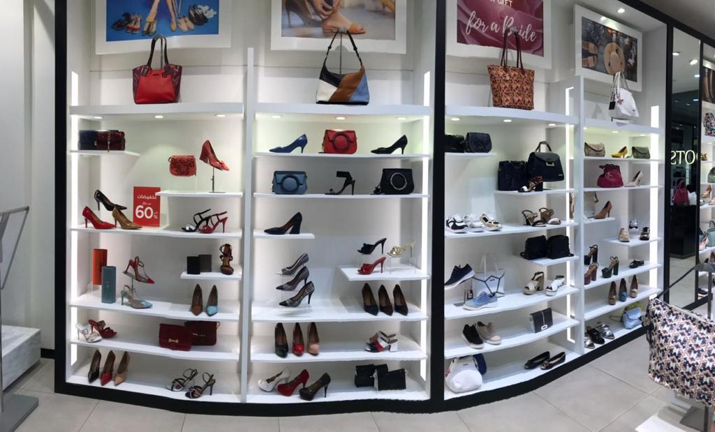 A well-lit display of women's shoes and handbags on shelves in a retail store.