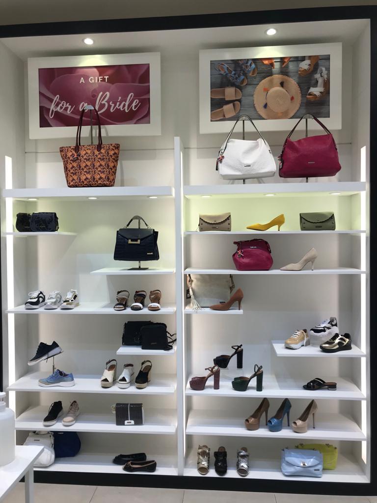 A retail display showcasing a variety of women's handbags and shoes on shelves.