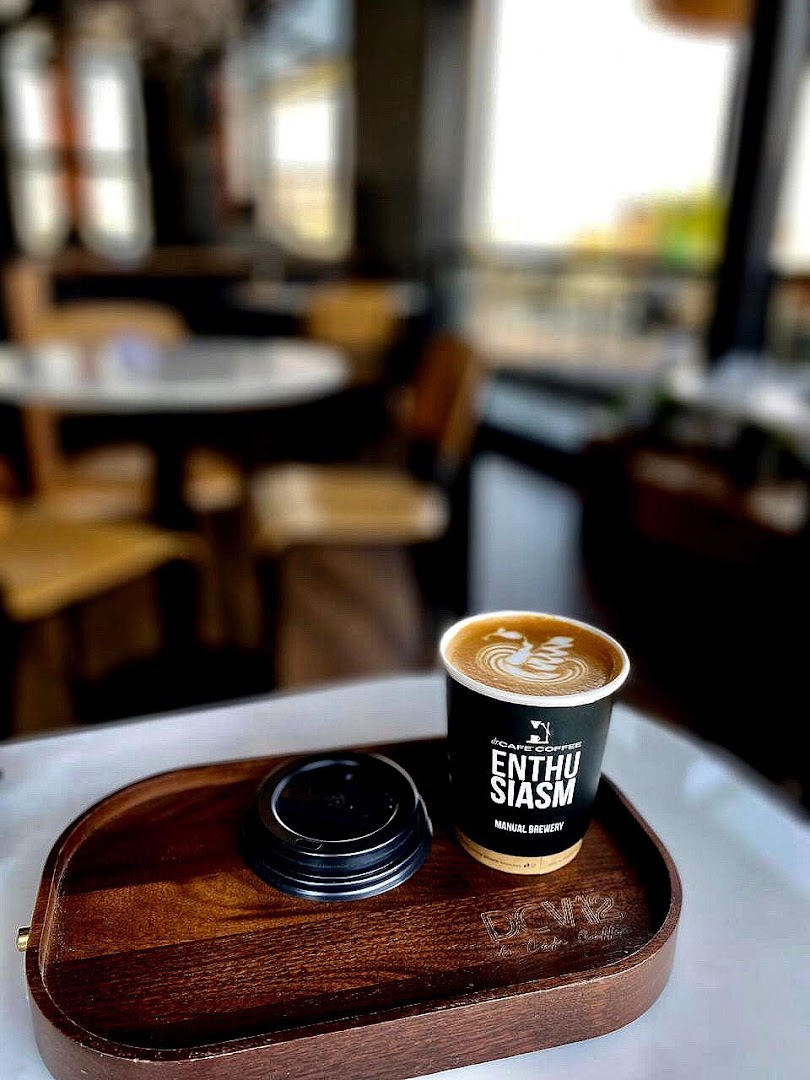 A cup of coffee with latte art on a wooden tray with a lid.