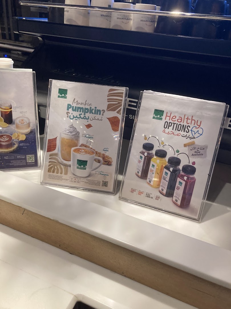Display stands showcasing pumpkin drinks and healthy juice options at a coffee shop.