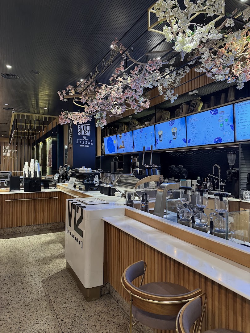 Interior of a modern coffee shop with cherry blossom decorations and digital menus.