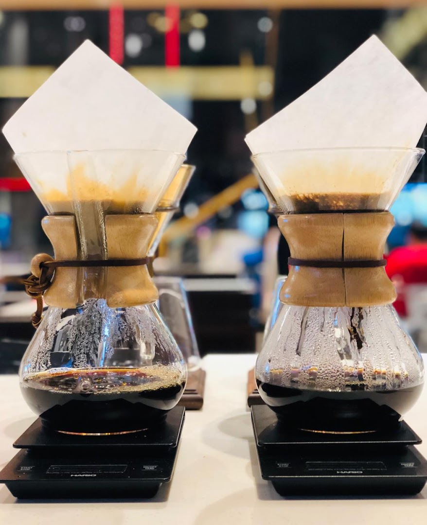 Two Chemex coffee makers with freshly brewed coffee on scales.