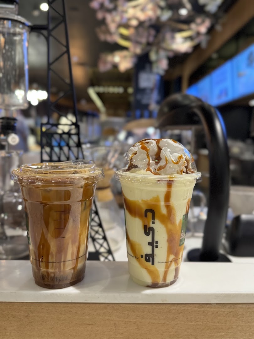 Two iced coffee drinks with caramel drizzle and whipped cream on a counter.