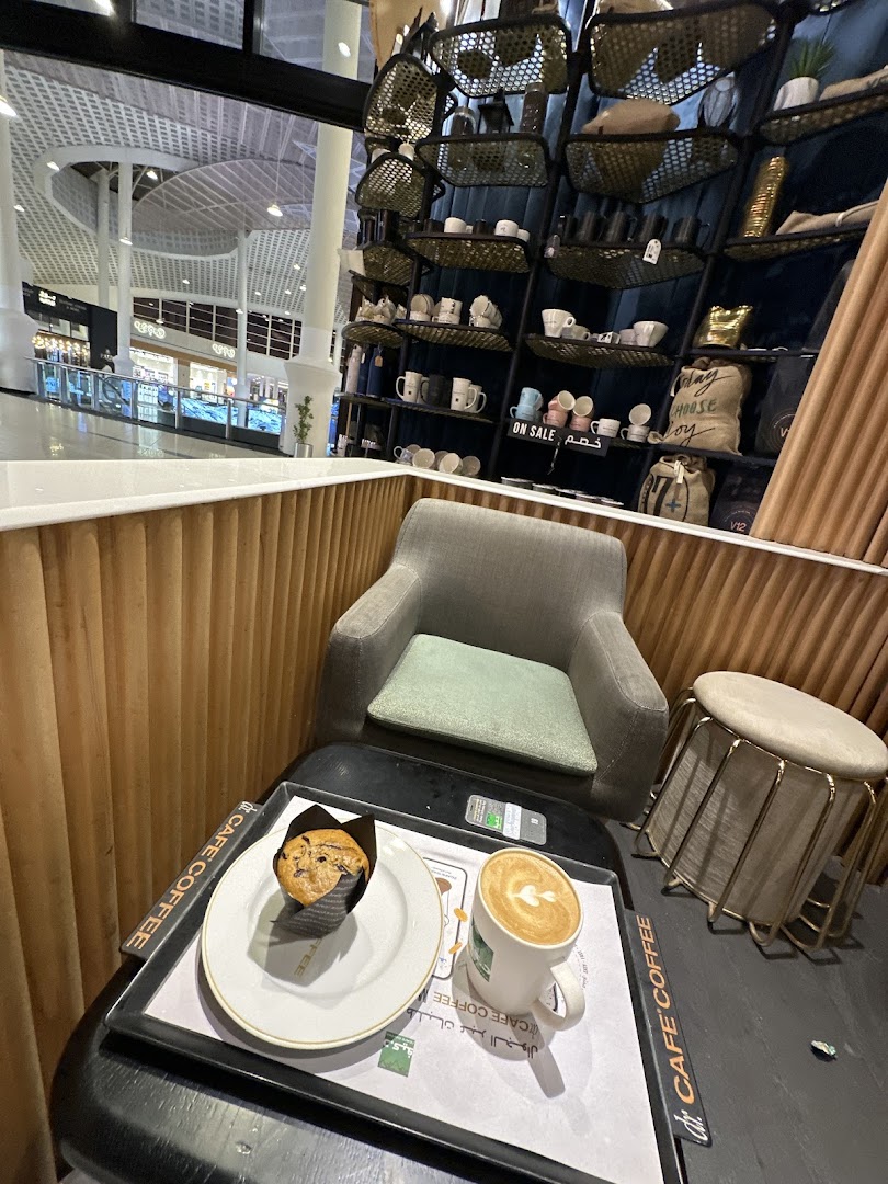 A cozy seating area at dr.CAFE COFFEE V12 Station with a muffin and latte.