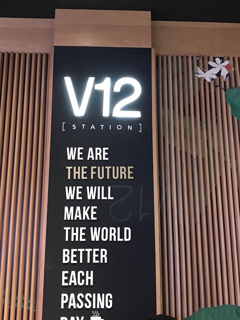 A sign for V12 Station with a motivational message about making the world better.