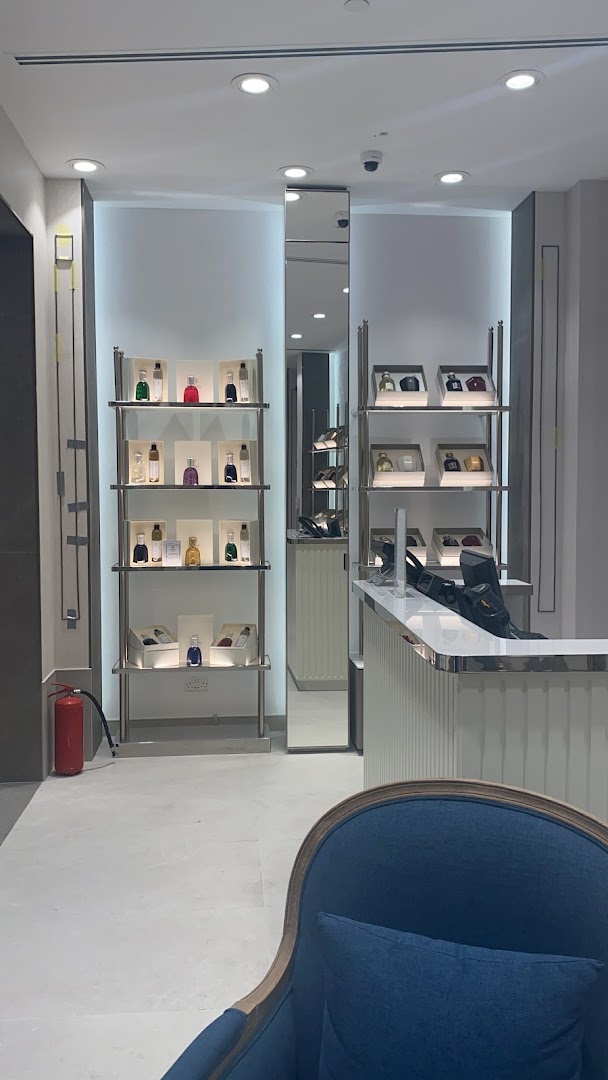 Interior of a luxury perfume shop with shelves displaying various fragrances and a modern counter.