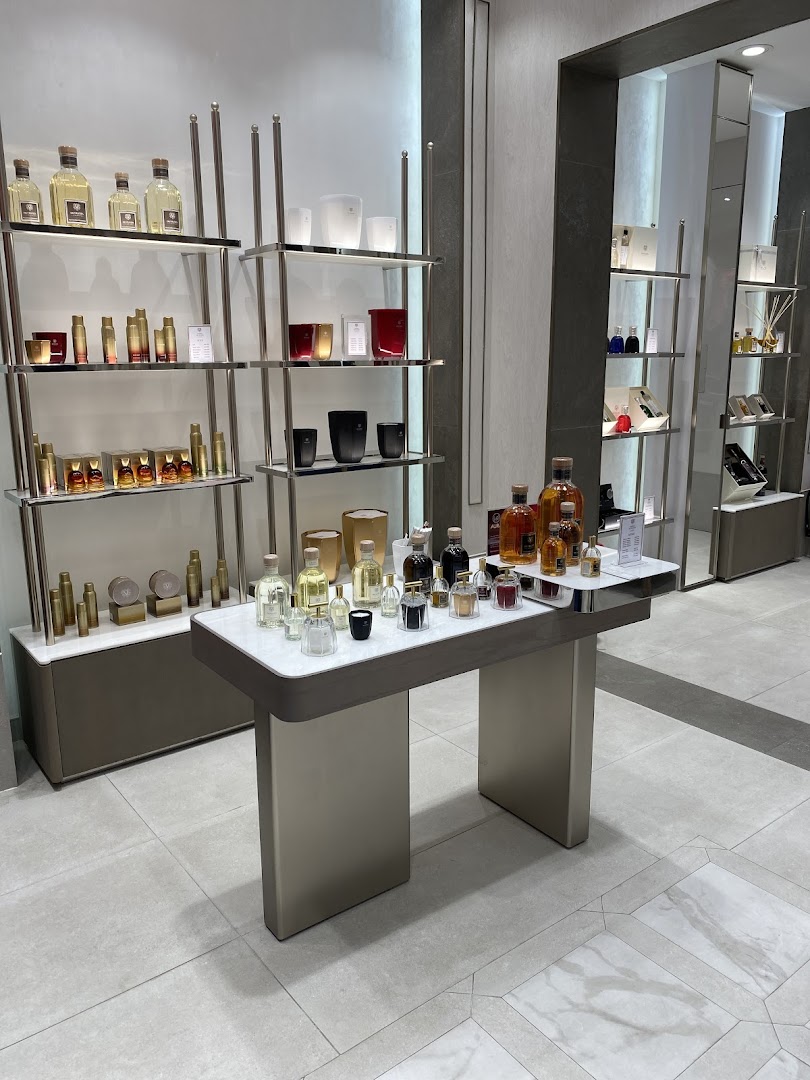 Interior of a luxury fragrance shop displaying various perfumes and home scents on shelves and a central table.